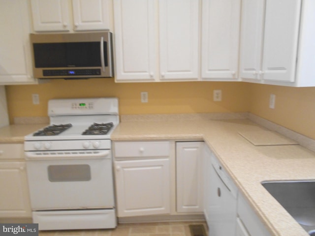 kitchen featuring white gas range, sink, and white cabinets