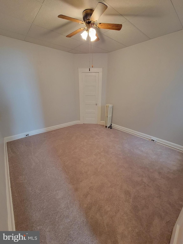 carpeted empty room with radiator heating unit and ceiling fan