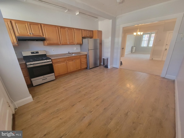 kitchen featuring appliances with stainless steel finishes, sink, a chandelier, crown molding, and light wood-type flooring