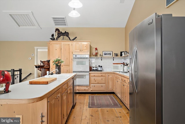 kitchen with double oven, stainless steel fridge, sink, and light brown cabinets