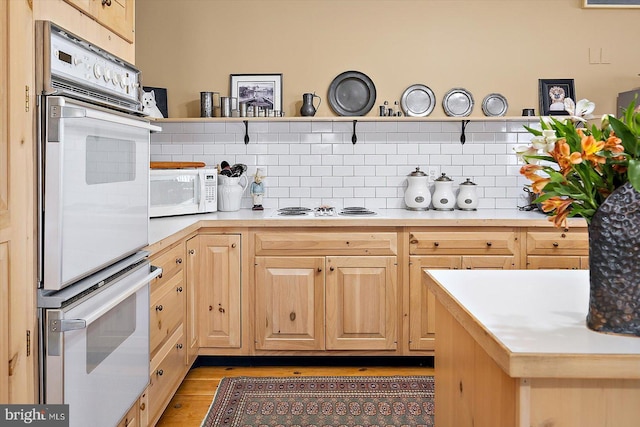 kitchen featuring tasteful backsplash, white appliances, light hardwood / wood-style floors, and light brown cabinets