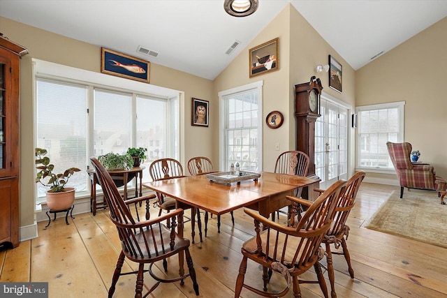 dining space featuring high vaulted ceiling and light wood-type flooring