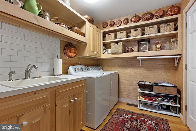 laundry area with sink, washer and clothes dryer, light hardwood / wood-style floors, and cabinets