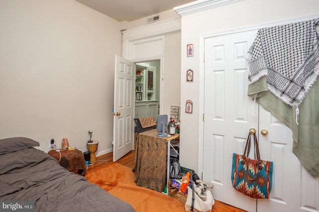 bedroom with baseboards, visible vents, and wood finished floors