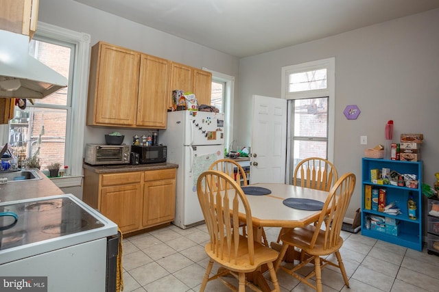 kitchen featuring under cabinet range hood, light tile patterned floors, a toaster, and white appliances