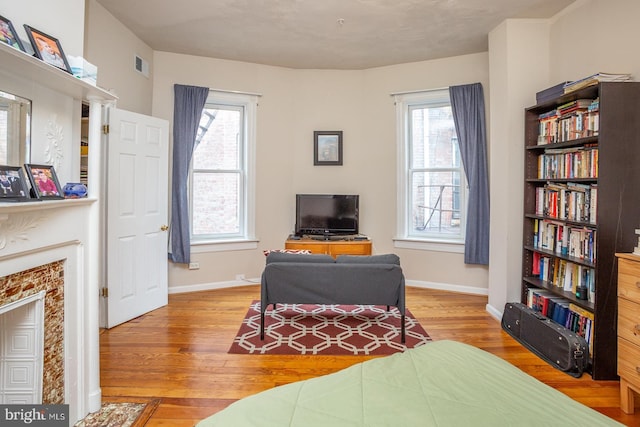 living area with visible vents, wood finished floors, baseboards, and a fireplace