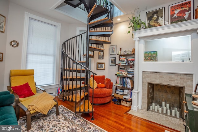 sitting room with wood finished floors, a brick fireplace, and stairs