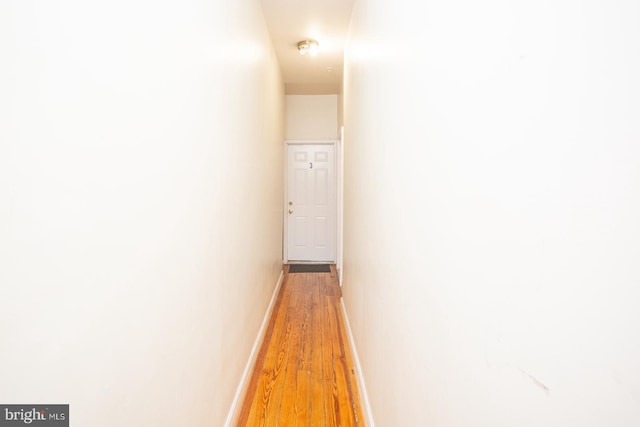 corridor featuring baseboards and light wood-style floors