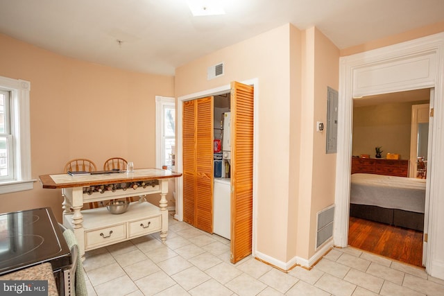 interior space featuring light tile patterned floors, baseboards, visible vents, and electric panel