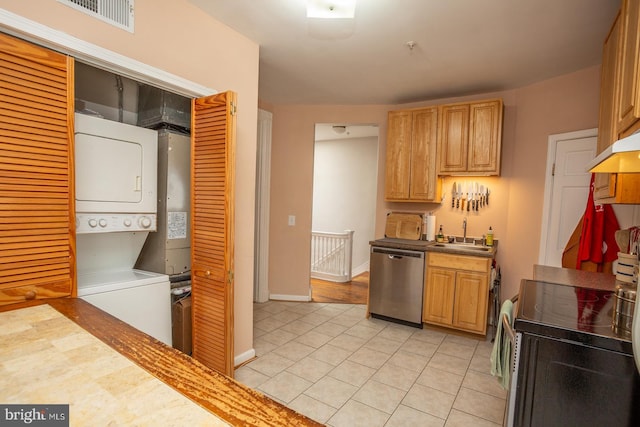 kitchen featuring a sink, stainless steel appliances, visible vents, under cabinet range hood, and stacked washing maching and dryer