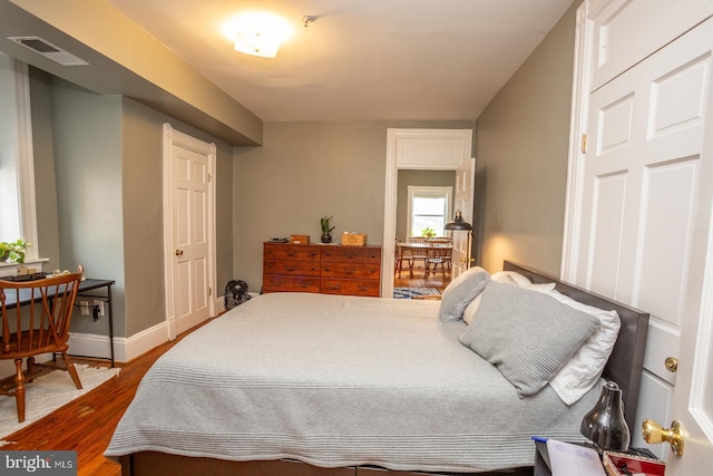 bedroom featuring baseboards, visible vents, and wood finished floors
