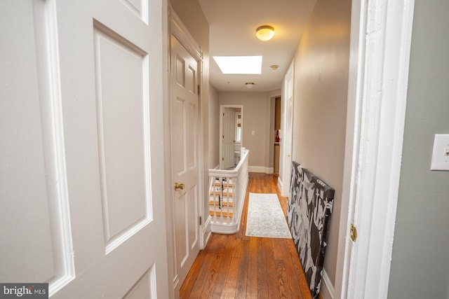 hall with light wood finished floors and a skylight