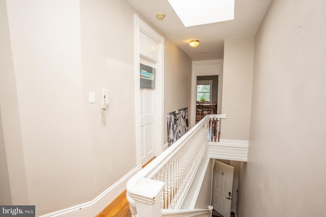 corridor with an upstairs landing and a skylight