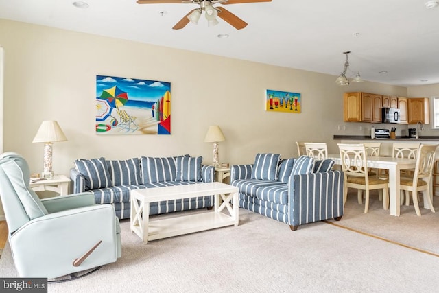 living room featuring light carpet, sink, and ceiling fan