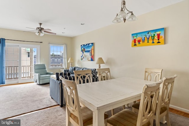 carpeted dining area with ceiling fan with notable chandelier