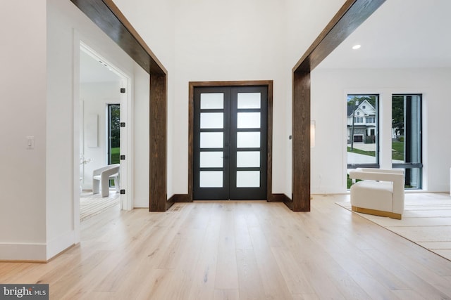 entrance foyer with a wealth of natural light, light hardwood / wood-style flooring, and french doors