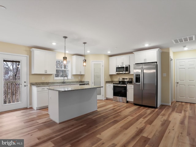 kitchen featuring pendant lighting, white cabinetry, appliances with stainless steel finishes, and a center island