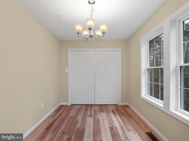 interior space with a closet, light hardwood / wood-style floors, multiple windows, and a notable chandelier