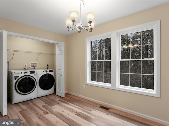 laundry area with an inviting chandelier, light hardwood / wood-style flooring, and washing machine and clothes dryer