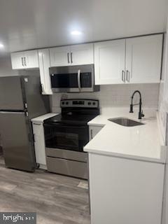 kitchen featuring white cabinetry, appliances with stainless steel finishes, sink, and light hardwood / wood-style flooring