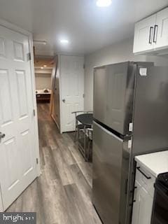 kitchen with stainless steel fridge, light wood-type flooring, and white cabinets