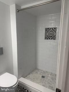 bathroom with tiled shower and toilet