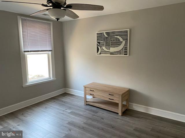 empty room with ceiling fan and dark hardwood / wood-style flooring