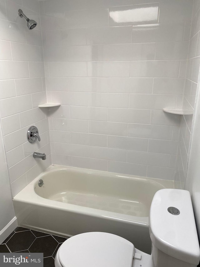 bathroom featuring tiled shower / bath, toilet, and tile patterned flooring