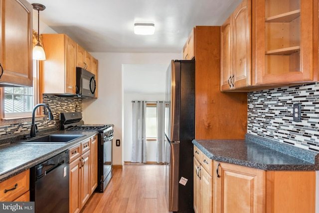 kitchen with black appliances, dark countertops, a sink, and decorative light fixtures