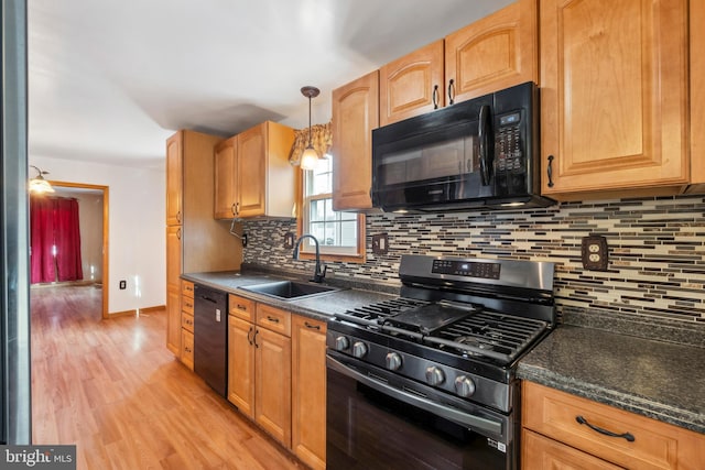 kitchen with decorative light fixtures, backsplash, a sink, light wood-type flooring, and black appliances