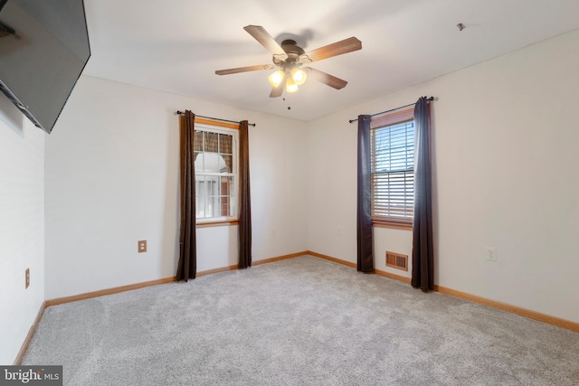 unfurnished room with light carpet, baseboards, visible vents, and a ceiling fan