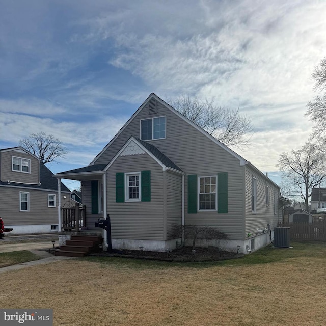 view of front of house with central AC and a front lawn