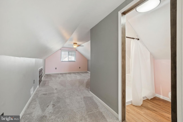 additional living space featuring lofted ceiling, light carpet, visible vents, and baseboards