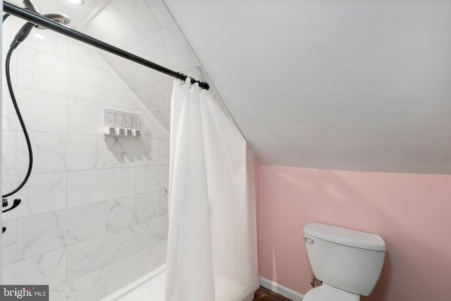 bathroom featuring vaulted ceiling, tiled shower, and toilet