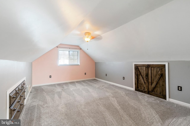 bonus room featuring baseboards, vaulted ceiling, and light colored carpet