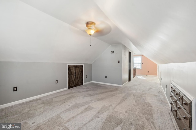 additional living space featuring lofted ceiling, light carpet, and baseboards