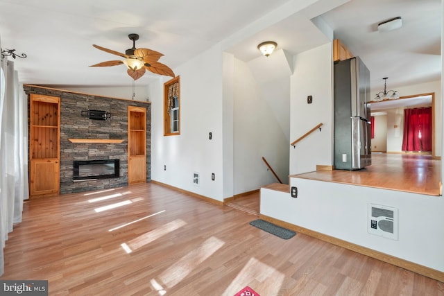 unfurnished living room featuring a fireplace, heating unit, ceiling fan, light wood-type flooring, and baseboards