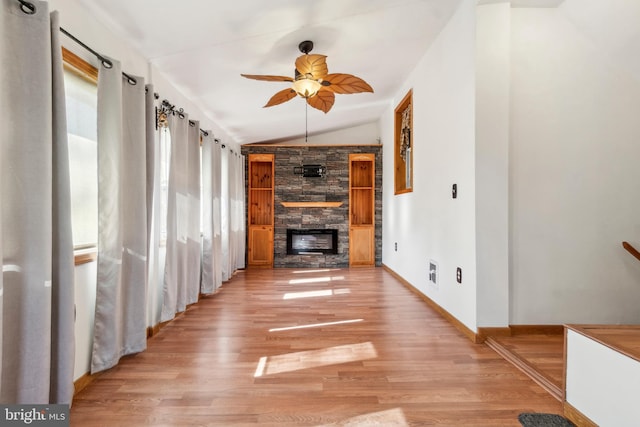 unfurnished living room featuring light wood-style flooring, a fireplace, a ceiling fan, baseboards, and vaulted ceiling