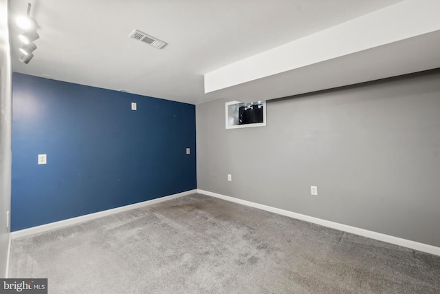 carpeted spare room with rail lighting, baseboards, and visible vents