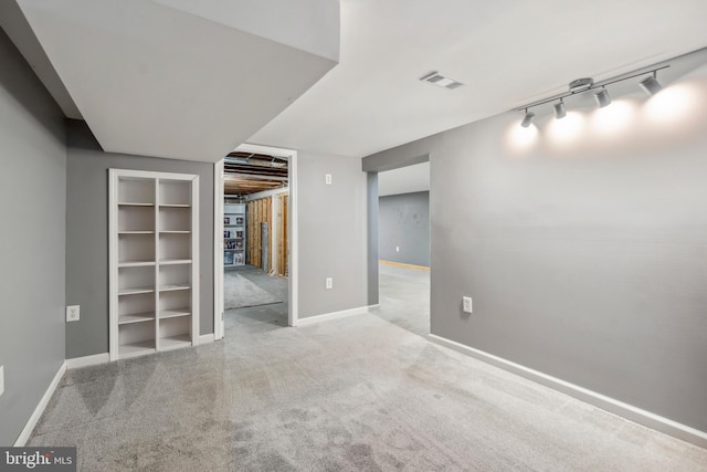 interior space with track lighting, light colored carpet, visible vents, and baseboards