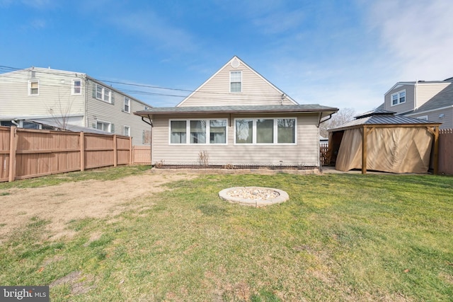 rear view of house with a yard, a gazebo, and fence