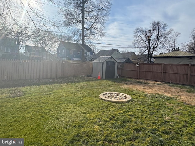 view of yard featuring a fenced backyard, a residential view, a storage unit, and an outbuilding