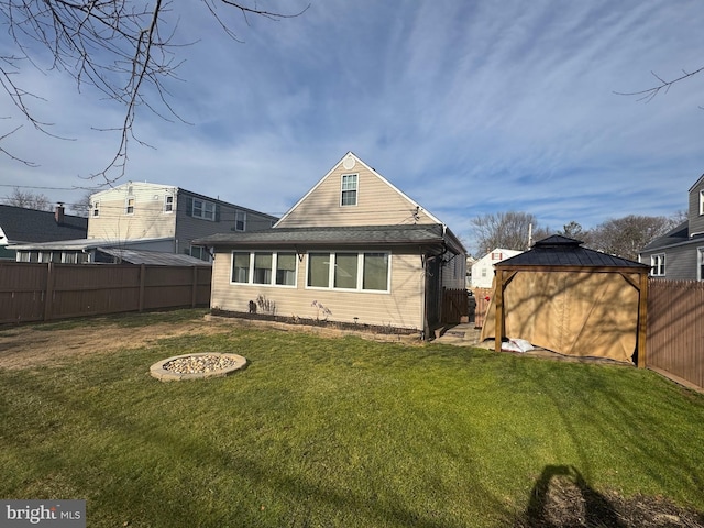 back of property featuring a yard, a gazebo, and an outdoor fire pit