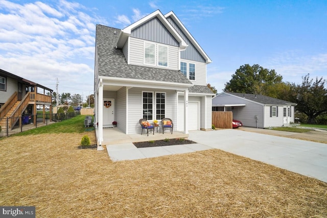 back of property featuring fence, concrete driveway, a yard, roof with shingles, and board and batten siding