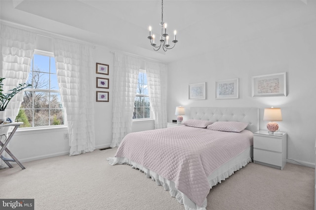 carpeted bedroom featuring multiple windows, an inviting chandelier, and a tray ceiling