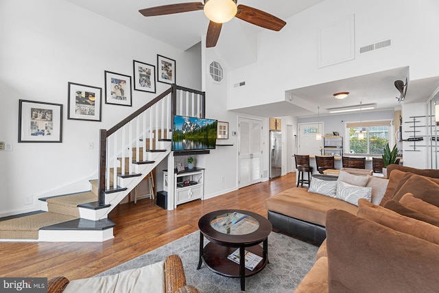 living room featuring a high ceiling, hardwood / wood-style floors, and ceiling fan