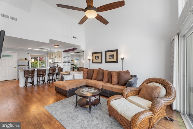 living room featuring hardwood / wood-style flooring, ceiling fan, and a high ceiling