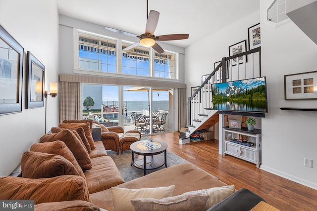 living room featuring wood-type flooring, ceiling fan, and a high ceiling