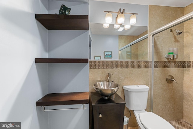 bathroom featuring toilet, a shower with shower door, tile walls, vanity, and backsplash