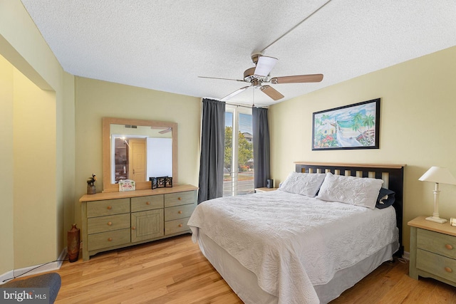 bedroom with ceiling fan, light hardwood / wood-style flooring, and a textured ceiling